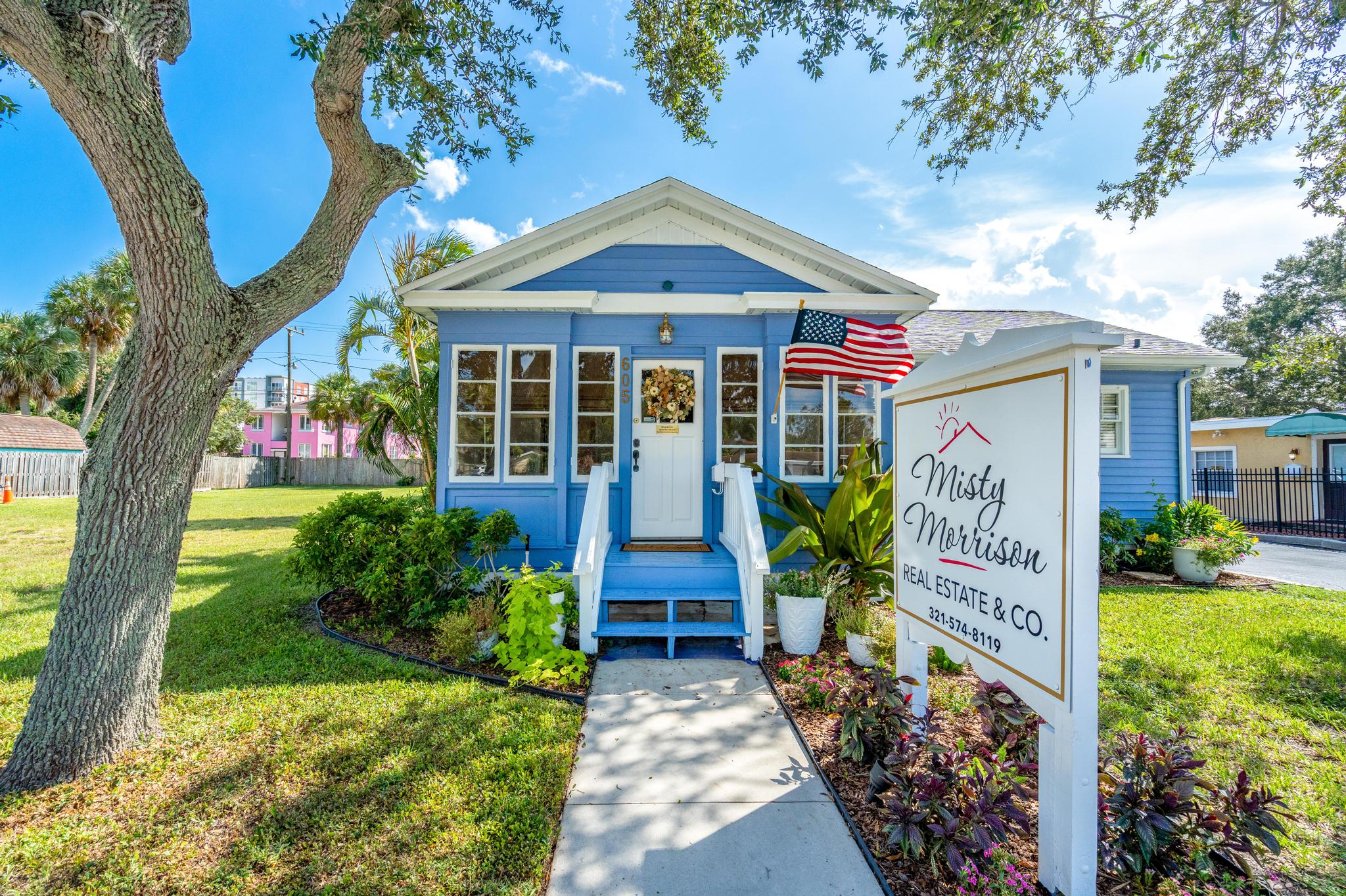 The Misty Morrison Real Estate and Company office, a blue cottage with a porch and flag