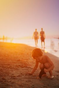 A boy picking up seashells on a beach.